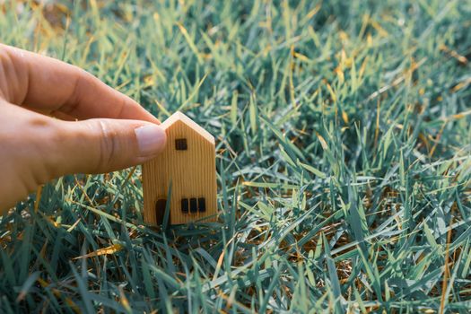 Closed up tiny home model on green grass with sunlight background.