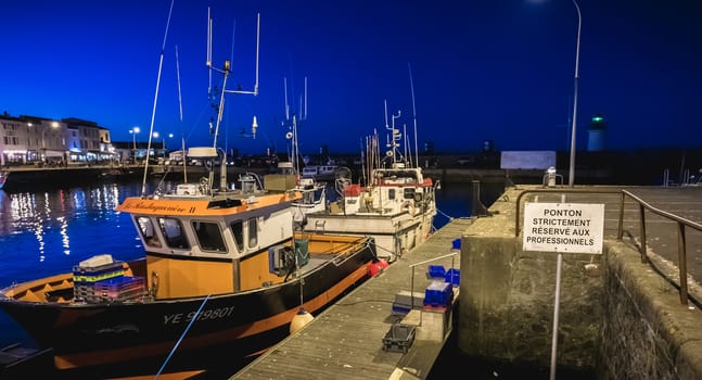 Port Joinville, France - September 19, 2018: view of the main port of the Yeu island with its picturesque architecture and its fishing boats at night on a fall day