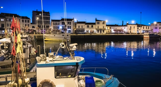 Port Joinville, France - September 19, 2018: view of the main port of the Yeu island with its picturesque architecture and its fishing boats at night on a fall day