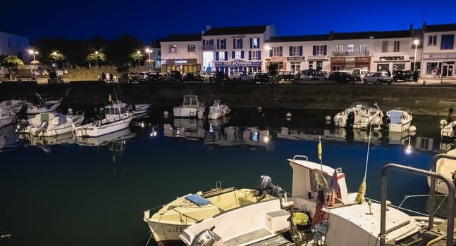 Port Joinville, France - September 19, 2018: view of the main port of the Yeu island with its picturesque architecture and its fishing boats at night on a fall day