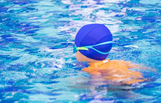 Wet suit Asian boy with swim glasses is swim in a pool