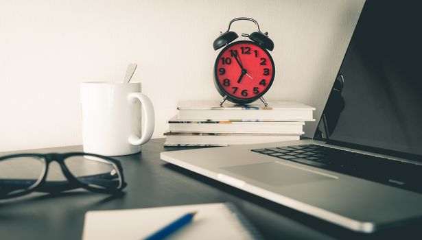 Red Alarm Clock on office table with objects