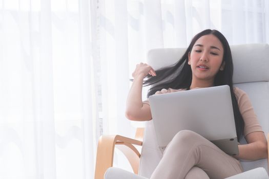 Young long hair Asian Girl using laptop on the Sofa