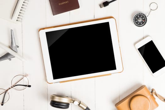 Blank tablet screen surrounded by travel equipment