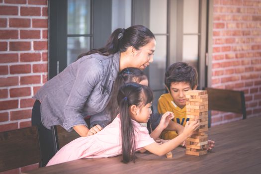 Children is building toy block tower with teacher