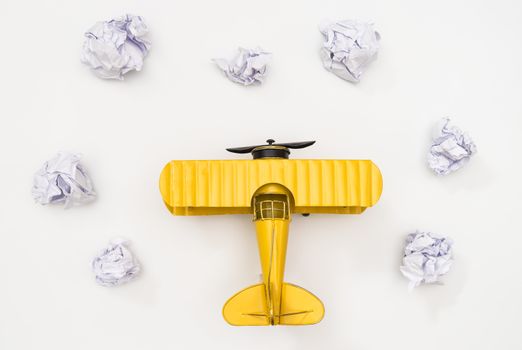 Toy plane on paper cloud on white background top view