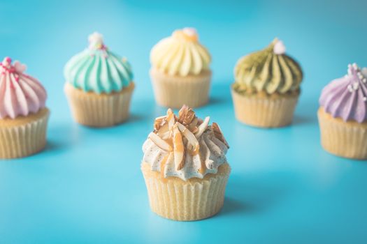 Almond Cupcake surrounding by colorful cupcakes on blue background