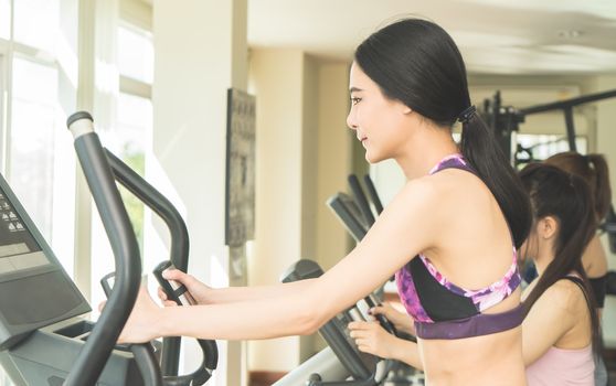 Asian woman is working out in fitness gym machine