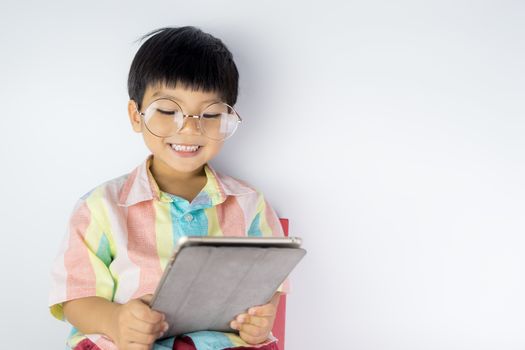 happy Asian kid is studying on tablet on white background