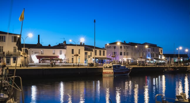 Port Joinville, France - September 19, 2018: view of the main port of the Yeu island with its picturesque architecture and its fishing boats at night on a fall day