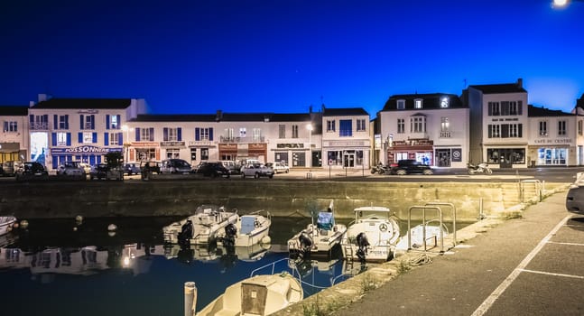 Port Joinville, France - September 19, 2018: view of the main port of the Yeu island with its picturesque architecture and its fishing boats at night on a fall day