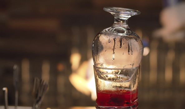 Close up glass with ready-made Raspberry Sambuca on the bacground of the fire. Steam rises from a hot drink. Bar drinks series