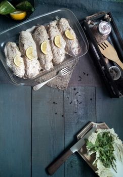 Marinated Turkey wings in a tray on a wooden table, prepared for roasting in the oven. There are spices and herbs nearby. Top view, copy space.