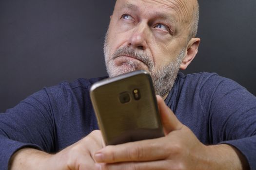 a man while reflecting before retweeting a message on his mobile phone