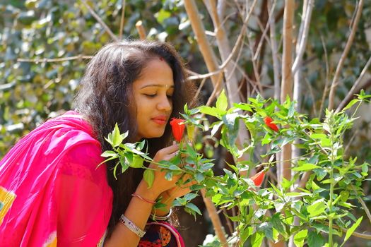 A girl smelling a hibiscus flower in the garden and polished red on the lips.