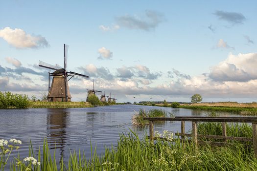 Alignement of reflection on a turbulent canal of a Dutch windmills landscape at Alblasserdam city during the warm sunrise, Netherlands