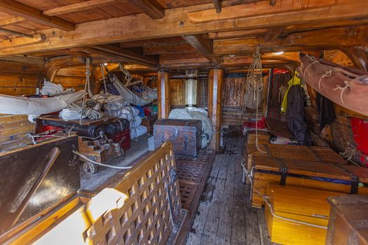 Inner view of a wooden pirate tall ship cabin with canon, chest and folded wings ready to sail away campaigning on the high sea