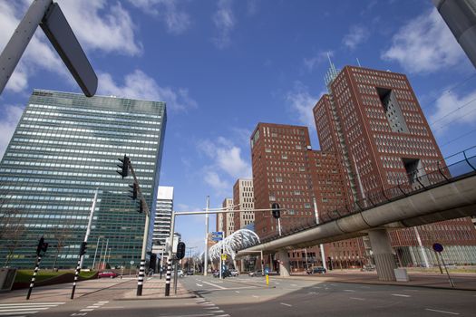 Up view of The Hague business center with the aerial tram rail bordered by tall corporate building under a pur cloudy sky, Netherlands