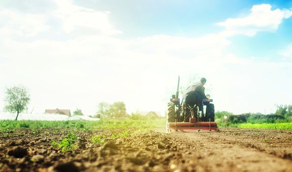 Farmer on a tractor with milling machine loosens, grinds and mixes soil. Loosening the surface, cultivating the land for further planting. Farming and agriculture. Cultivation technology equipment