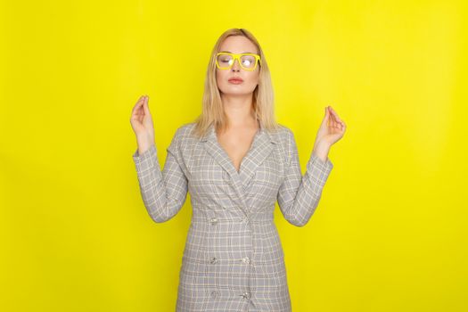 Attractive blonde woman in plaid jacket dress over yellow background wearing yellow glasses