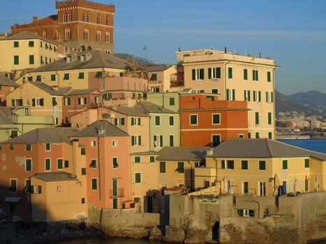 An amazing caption of the sunset in winter days over the sea of Genova with beautiful red and blue sky, some amazing clouds in the background and old rocks over the sea.