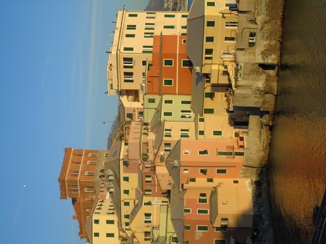 An amazing caption of the sunset in winter days over the sea of Genova with beautiful red and blue sky, some amazing clouds in the background and old rocks over the sea.