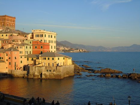 An amazing caption of the sunset in winter days over the sea of Genova with beautiful red and blue sky, some amazing clouds in the background and old rocks over the sea.