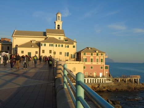 An amazing caption of the sunset in winter days over the sea of Genova with beautiful red and blue sky, some amazing clouds in the background and old rocks over the sea.