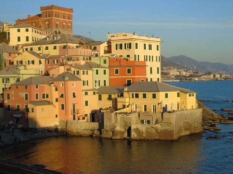 An amazing caption of the sunset in winter days over the sea of Genova with beautiful red and blue sky, some amazing clouds in the background and old rocks over the sea.