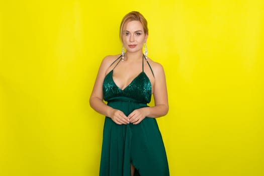 Fashion picture of beautiful young blonde woman wearing green evening dress. Elegant woman ready fo evening