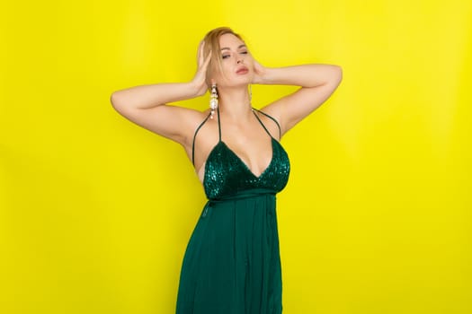 Fashion picture of beautiful young blonde woman wearing green evening dress. Elegant woman ready fo evening