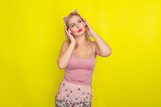 Blonde woman in pink summer clothing wearing pink headphones like kitten ears