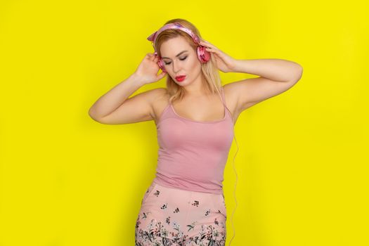 Blonde woman in pink summer clothing wearing pink headphones like kitten ears