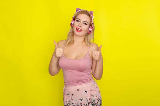 Blonde woman in pink summer clothing wearing pink headphones like kitten ears