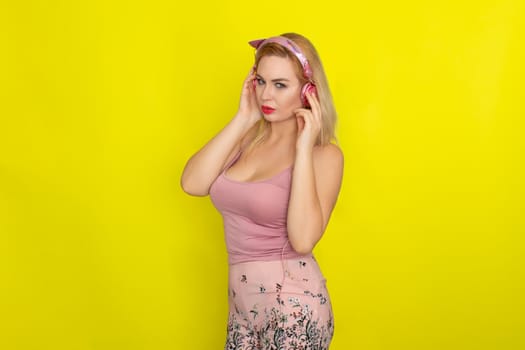 Blonde woman in pink summer clothing wearing pink headphones like kitten ears