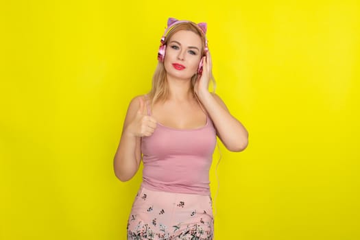 Blonde woman in pink summer clothing wearing pink headphones like kitten ears