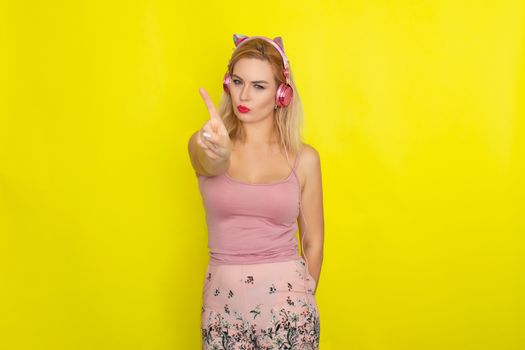 Blonde woman in pink summer clothing wearing pink headphones like kitten ears