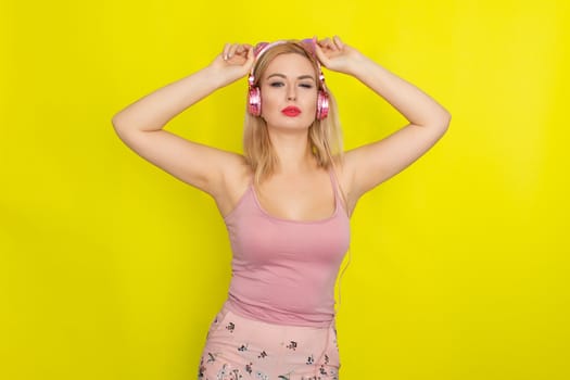 Blonde woman in pink summer clothing wearing pink headphones like kitten ears