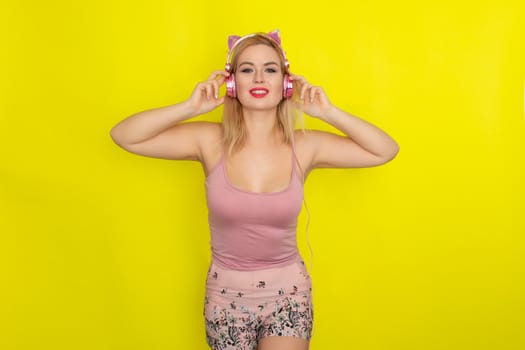 Blonde woman in pink summer clothing wearing pink headphones like kitten ears