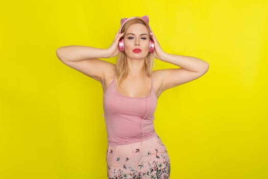 Blonde woman in pink summer clothing wearing pink headphones like kitten ears