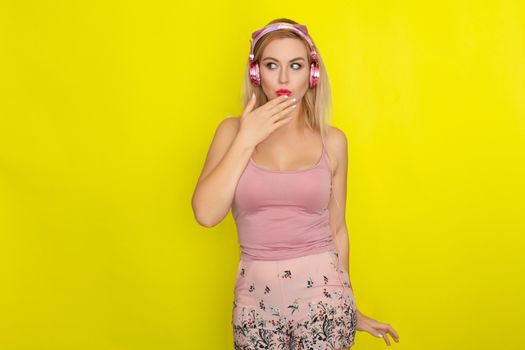 Blonde woman in pink summer clothing wearing pink headphones like kitten ears