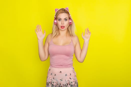 Blonde woman in pink summer clothing wearing pink headphones like kitten ears