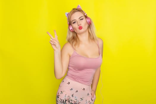 Blonde woman in pink summer clothing wearing pink headphones like kitten ears