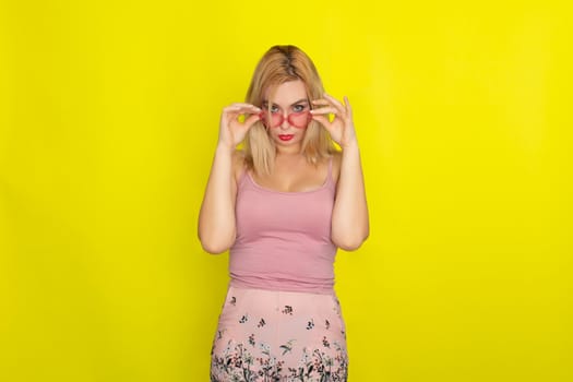 Blonde woman in summer street clothing wearing sunglasses like hearts