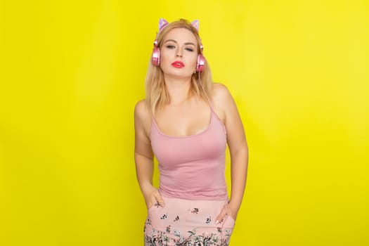 Blonde woman in pink summer clothing wearing pink headphones like kitten ears