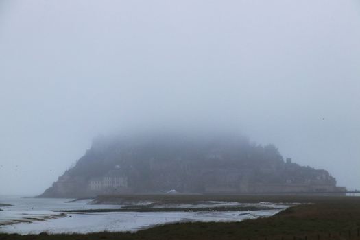 Panoramic views of Mont Saint Michel in a foggy morning. Stratified fog and suggestive view of the place