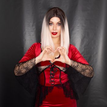 Portrait of a young blonde woman in a red vampire costume on a black background in the studio