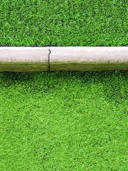 Texture of plastic artificial grass and the concrete border of school yard