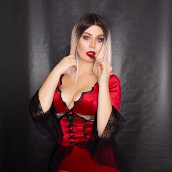 Young beautiful blonde woman in a red vampire dress and with a scorpion on her body in the studio