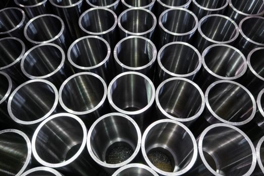 dark industrial background with cnc machined shiny steel pipes - selective focus and lens blur technique